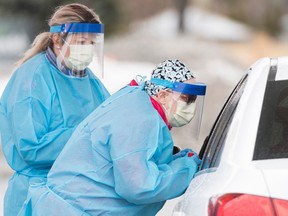 Healthcare workers talk to a driver before issuing a test at a drive-thru COVID-19 evaluation clinic in Montreal, Sunday, March 29, 2020, as Coronavirus COVID-19 cases rise in Canada and around the world.