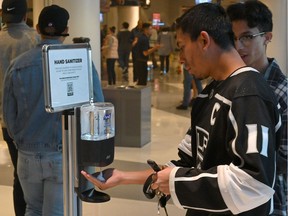Fans use a hand sanitizer station at the Staples Center before a game between the Los Angeles Kings and the Ottawa Senators on Wednesday, March 11, 2020.