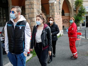 People wearing protective masks line up to donate blood after appeals from hospitals and the Italian government for blood donations to help treat coronavirus patients, at an Italian Red Cross centre, in Rome, Italy, Tuesday, March 17 2020.