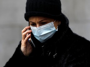 In this file photo, a woman in a surgical mask uses her cellphone after more cases of coronavirus were confirmed in Manhattan, New York City, March 11, 2020.
