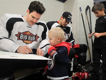 YELLOWKNIFE, N.W.T. NOVEMBER 18,  2012 --- A number of Ottawa Senators and other NHL players arrived in Yellowknife in the Northwest Territories Sunday to begin their Northern Lights Dream Tour, which will include three exhibition games in Yellowknife, Inuvik, and Whitehorse (Yukon). Here,  Jim Slater (Winnipeg) signs a big card from tiny autograph seeker, Kadric Mujcin, 2, following the game.