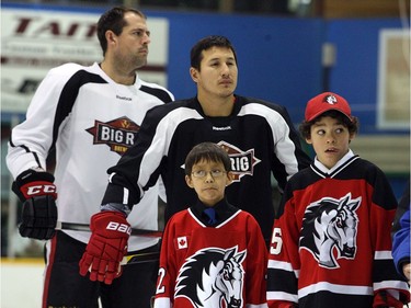 WHITEHORSE, YUKON. NOVEMBER 21,  2012 --- Chris Phillips (left) and Jordan Tootoo stand over some young hockey players during the opening ceremony for their last game in Whitehorse.   The Northern Lights Dream Tour wound up Wednesday with a final game in Whitehorse, Yukon, followed by long flights home on Thursday for the players - many with three connections and 15 to 20 hours in the air.