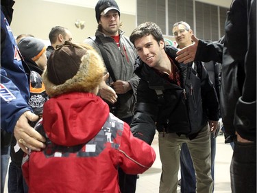 YELLOWKNIFE, N.W.T. NOVEMBER 18,  2012 --- A number of Ottawa Senators and other NHL players arrived in Yellowknife in the Northwest Territories Sunday to begin their Northern Lights Dream Tour, which will include three exhibition games in Yellowknife, Inuvik, and Whitehorse (Yukon). Here, Dartmouth College goalie Jody O'Neil shakes a young fan's hand upon arriving at the airport in Yellowknife as Guillaume Latendresse (left)  looks on.