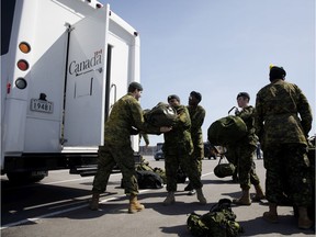 Members of the Canadian Forces pack buses at Denison Armory to convoy to CFB Borden amid the spread of COVID-19 on April 6, 2020 in Toronto.