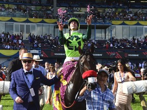 Jockey Flavien Prat, on top of One Bad Boy, throws flower petals in the air after winning the 160th Queen's Plate at Woodbine Racetrack, in Toronto on Saturday, June 29, 2019. THE CANADIAN PRESS/Frank Gunn