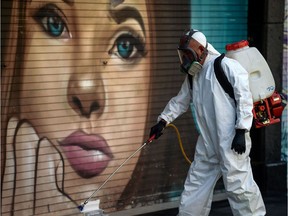 A cleaning worker wearing PPE (personal protective equipment) disinfects a street in Mexico City's historic center on April 6, 2020. (Photo by PEDRO PARDO / AFP)