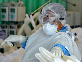 A nurse assists a patient infected with COVID-19.