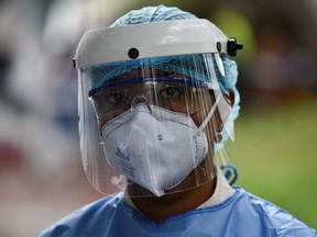 A health worker wears a face mask and shield.