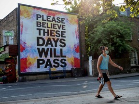A pedestrian walks past a billboard reading "Please believe these days will pass" at Broadway Market in London, England, on Friday, April 24, 2020.