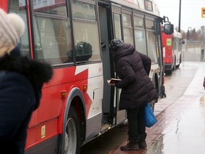 A commuter gets on an OC Transpo bus through the rear door.