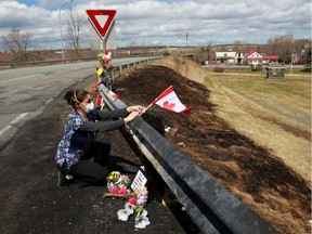 Care worker and first responder Alicia Cunningham adjusts a Canadian flag that had blown off the guardrail at a makeshift memorial for Royal Canadian Mounted Police (RCMP) Const. Heidi Stevenson, who was shot dead during a killing spree that worked its way across several Nova Scotian communities.