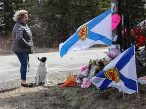 Denise Caume and her dog, Mimi, are seen in front of a makeshift memorial made after the mass shooting in Portapique, N.S.