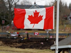 A Canadian flag flies at half-staff backdropped by the makeshift memorial for Royal Canadian Mounted Police (RCMP) Constable Heidi Stevenson, who was shot dead along with multiple others, in Shubenacadie, near Enfield, Nova Scotia, Canada April 22, 2020.