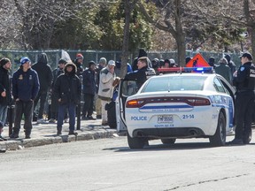 Police remind people to keep their social distance as they lineup to get into a homeless shelter March 31, 2020 in Montreal.