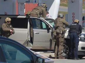 RCMP officers prepare to take a person into custody at a gas station in Enfield, N.S. on Sunday April 19, 2020.