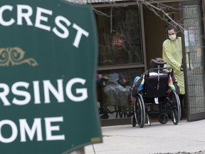 A staff member wearing personal protective equipment helps a patient back into the Pinecrest Nursing Home in Bobcaygeon where it's believed three residents have died of COVID-19, 14 healthcare workers have tested positive, and 35 more patients are experiencing symptoms, on Saturday, March 28, 2020. (Stan Behal/Toronto Sun/Postmedia Network)