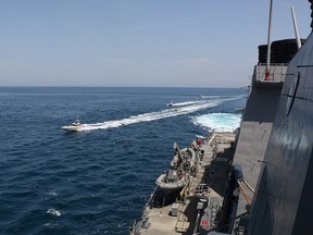 Four Iranian Islamic Revolutionary Guard Corps Navy (IRGCN) vessels, some of several to manoeuvre in what the U.S. Navy says are "unsafe and unprofessional actions against U.S. Military ships by crossing the ships’ bows and sterns at close range" is seen next to the guided-missile destroyer USS Paul Hamilton in the Gulf April 15, 2020.