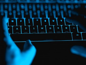 Hacker typing on the illuminated keyboard by night.