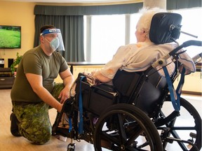 In this image obtained from Canadian Armed Forces Combat Camera, a Canadian soldier aids a senior citizen on May 10, 2020.