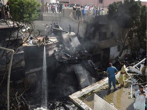 Firefighters spray water on the wreckage of a Pakistan International Airlines aircraft after it crashed at a residential area in Karachi on May 22, 2020. - A Pakistani passenger plane with nearly 100 people on board crashed into a residential area of the southern city of Karachi on May 22.