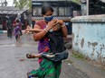 A woman carries her son as she tries to protect him from heavy rain while they rush to a safer place, following their evacuation from a slum area before Cyclone Amphan makes its landfall, in Kolkata, India, May 20, 2020.