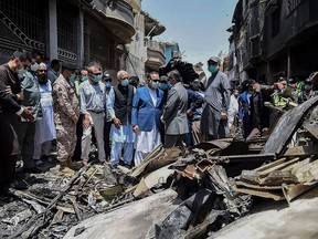 In this picture taken on May 23, 2020, and released by Pakistan Civil Aviation Authority (PCAA), Pakistan's Aviation Minister Ghulam Sarwar Khan (C-L in black jacket) visits along with Governor of Province Sindh, Imran Ismail (C-R in blue jacket), at the site a day after a Pakistan International Airlines aircraft crashed in a residential area in Karachi.