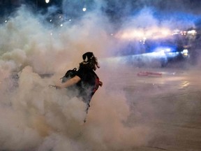 A protester hurls a tear gas canister back towards the police after tensions were sparked by arrests of protesters, through the streets of Detroit, for a second night, on Saturday, May 30,2020 to protest the death of George Floyd who was killed by a white officer who held his knee on his neck for several minutes.
