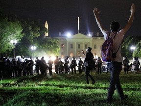 A protester holds his hands up as police officers enter Lafayette Park during a demonstration against the death in Minneapolis police custody of African-American man George Floyd, as the officers keep demonstrators away from the White House during a protest in Washington, D.C., early Saturday, May 30, 2020.