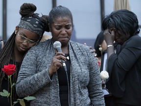 Ashton Dickson's mother, Donna Dickson (far right), wipes away tears as his aunt, Jacqueline Britto (centre) also chokes back emotion while addressing the crowd at a candlelight vigil for Ashton Dickson.