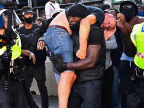 A protester carries an injured counter-protester to safety, near the Waterloo station during a Black Lives Matter protest following the death of George Floyd in Minneapolis police custody, in London, June 13, 2020.