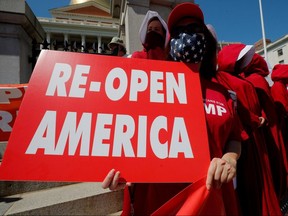 A woman holds a sign reading 'Re-Open America' at a demonstration to demand lifting of restrictions imposed by state and local officials in Boston, Massachusetts, U.S., May 30, 2020.