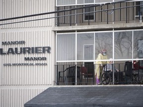 A health care worker wearing personal protective equipment (PPE) works with a resident on a balcony at the Laurier Manor in Ottawa, a long term care facility experiencing an outbreak of COVID-19, on Sunday, April 26, 2020.