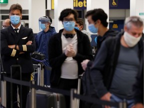 Passengers wearing face masks line up to check in at Manchester Airport in England in a file photo from earlier this month.