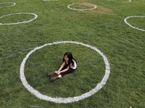 A girl sits in a park where circles were painted to help  maintain social distancing.
