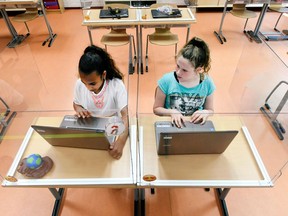 FILE PHOTO: Pupils sitting behind partition boards made of plexiglass attend a class at a primary school, during the COVID-19 outbreak, in  Netherlands, May 8, 2020.