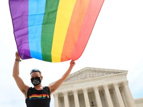 Joseph Fons, holding a Pride Flag, stands in front of the U.S. Supreme Court building after the court ruled that a federal law banning workplace discrimination also covers sexual orientation, in Washington, D.C., Monday, June 15, 2020.