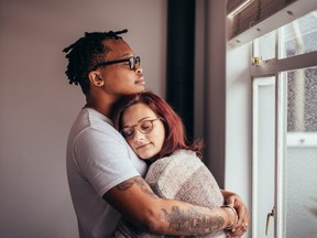 Interracial couple hugging near window