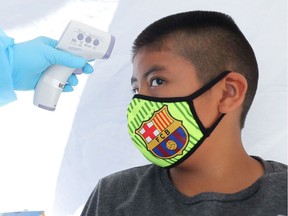 A boy has his temperature checked as he receives a COVID-19 test in Los Angeles.