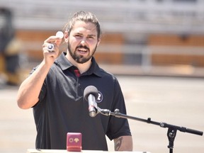 Redblacks player Antoine Pruneau displays the 2016 coin that was buried under a new playing surface at TD Place stadium on Tuesday.