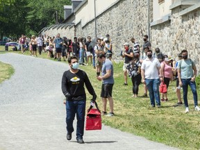 A food delivery driver walks past as hundreds of people line up at the COVID-19 testing clinic Wednesday, July 15, 2020 in Montreal.