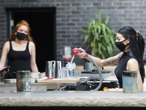 Bartender Alicia Mattoe, right, makes a drink as patrons sit on the patio at Joey Sherway, part of the Joey Restaurant chain during the COVID-19 pandemic in Toronto on Wednesday, June 24, 2020. Toronto and the GTA entered stage two of opening.
