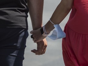 A couple holds hands with a mask.