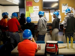 Temporary foreign workers stand in front of a job posting board during their lunch break at the Highline Mushrooms farm, Canada's largest mushroom grower, in Leamington, Ont., April 14, 2016.