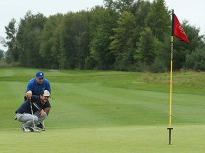 Eric Glynn (in blue) and Jordan McKenna line up a birdie putt on the third hole of the Talon course at GreyHawk on Saturday.