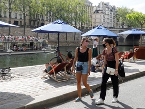 Pedestrians wearing protective face masks walk along the Seine river banks, as France reinforces mask-wearing as part of efforts to curb a resurgence of the coronavirus disease across the country, Paris, Aug. 15, 2020.