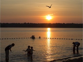 Files: The setting sun cast a glow across Westboro Beach on the Ottawa River as a number of bathers take advantage of the cool river to escape the heat.