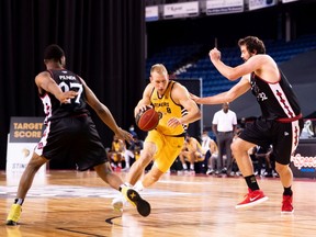 Jordan Baker of the  Stingers drives between Lloyd Pandi (left) and Kyle Landry (32) of the BlackJacks during Saturday's game. Baker finished the contest with 13 points.