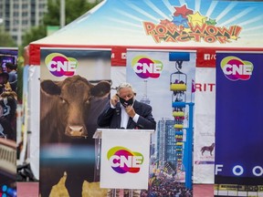 John Kiru, president of the Canadian National Exhibition, puts on a mask during the opening ceremonies of CNE At Home: The Virtual Fair @ TheEx.com by the Princes' Gates in Toronto, Ont. on Friday, Aug. 21, 2020.