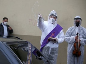 Mauricio Castiblanco, a Catholic deacon wearing protective gear, conducts a farewell ceremony for a deceased person outside the Chapinero cemetery, amidst an outbreak of the coronavirus disease (COVID-19), in Bogota, Colombia August 10, 2020. Picture taken August 10, 2020. REUTERS/Luisa Gonzalez ORG XMIT: GGGLFG12