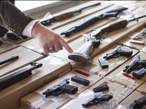 A police officer points out a fire arm as police display guns seized during a series of raids at a press conference in Toronto on June 14, 2013.